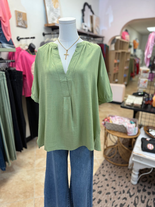 Mannequin wearing a green blouse and blue jeans in a store setting