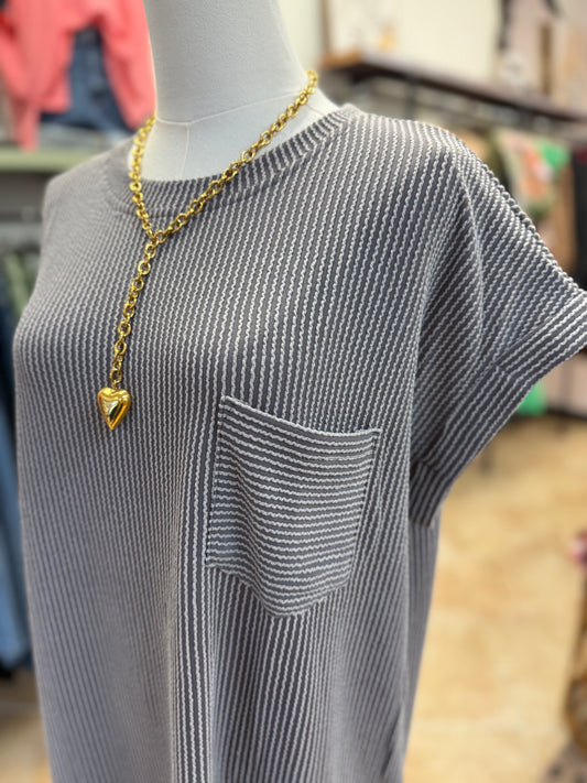 Uo close of mannequin wearing a gray ribbed dress with a gold necklace featuring a heart pendant.