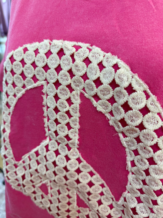 Peace symbol embroidered on a pink fabric background