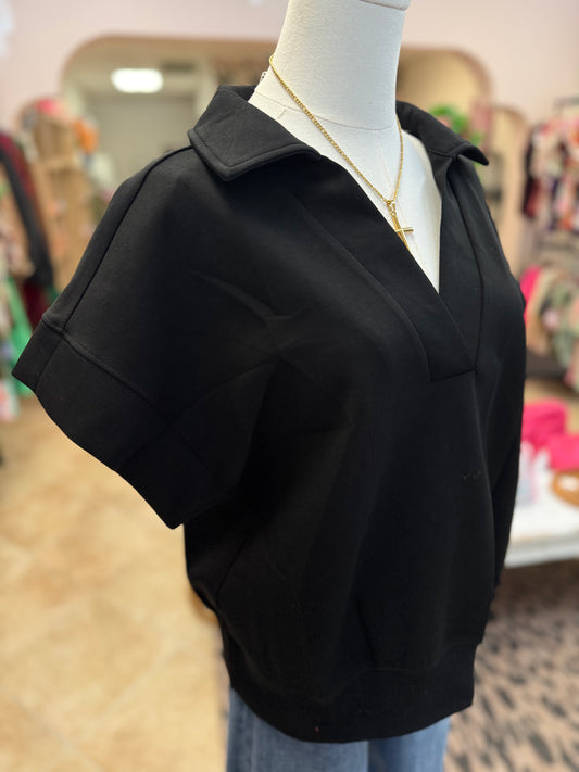 Black short-sleeve top on a mannequin with a blurred store background