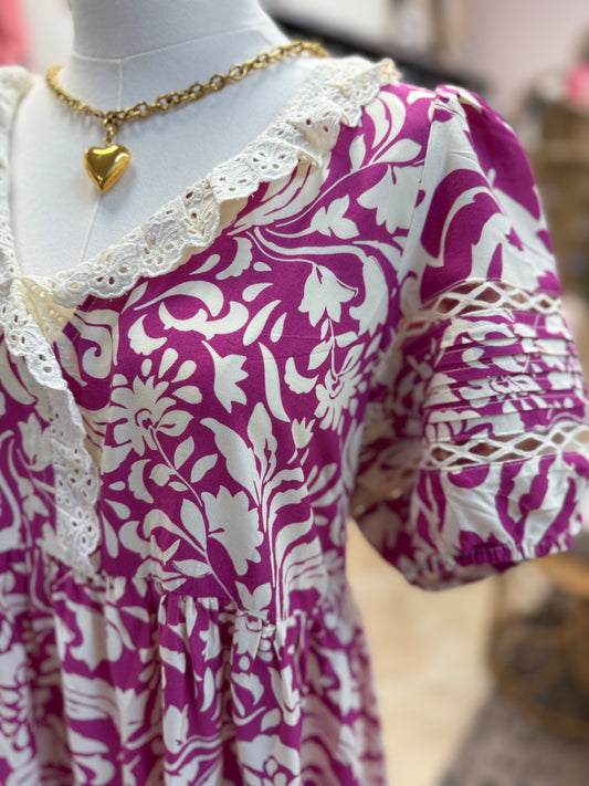 Mannequin wearing a purple and white patterned dress with a gold necklace.