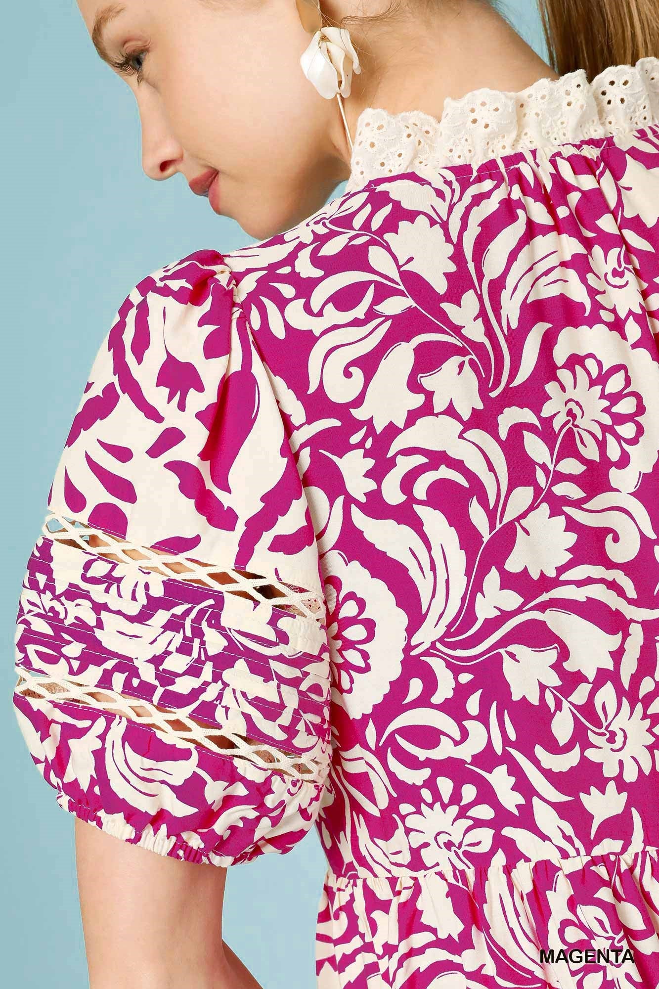 Close-up of a person wearing a pink and white floral patterned dress with lace details.