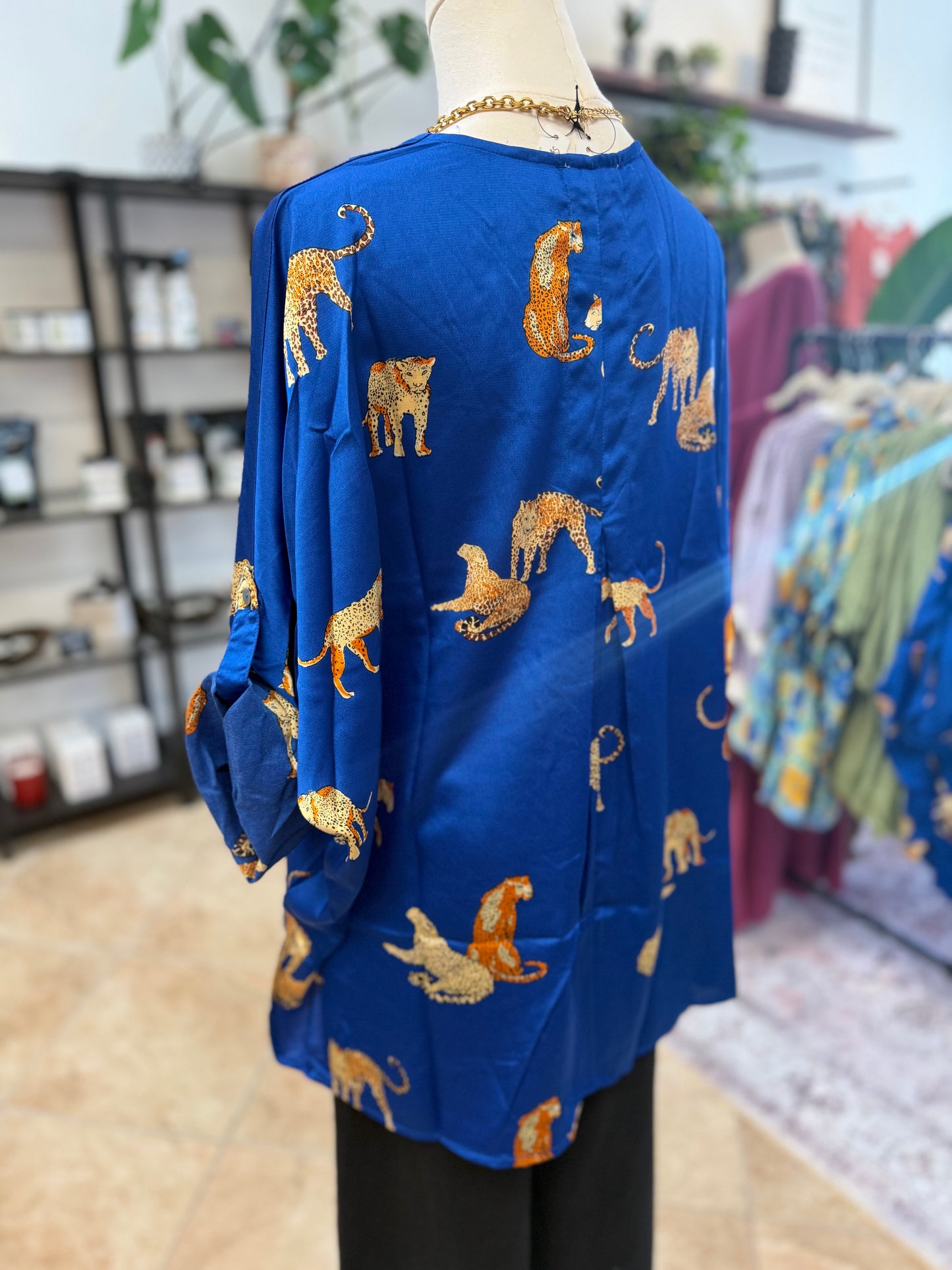 Blue cardigan with orange leopards on a mannequin in a store setting