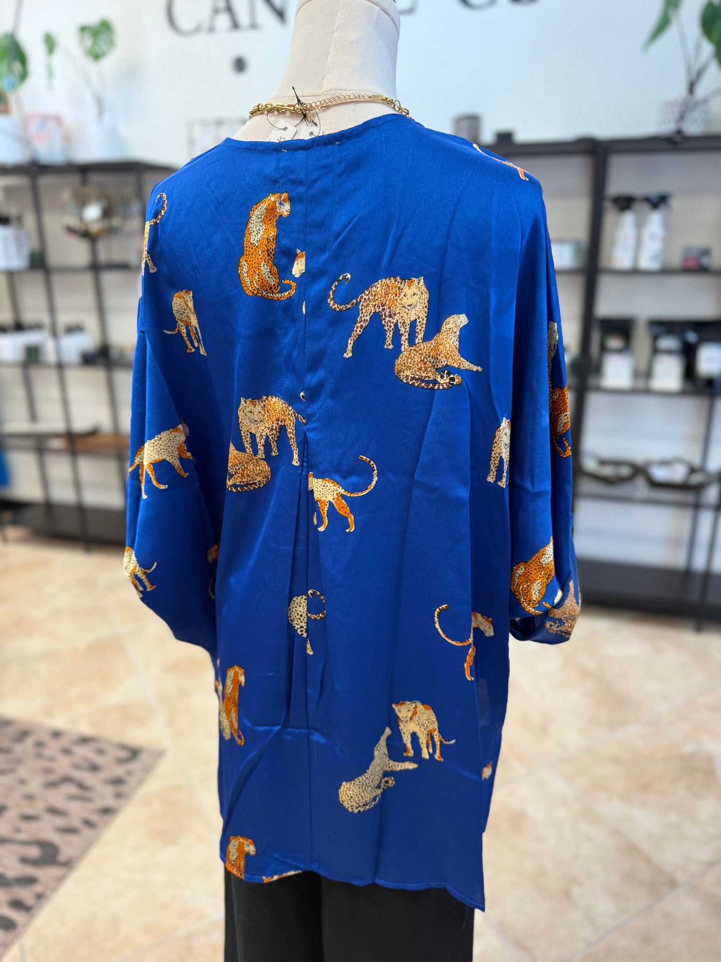 Blue blouse with gold tiger pattern on a mannequin against a store background