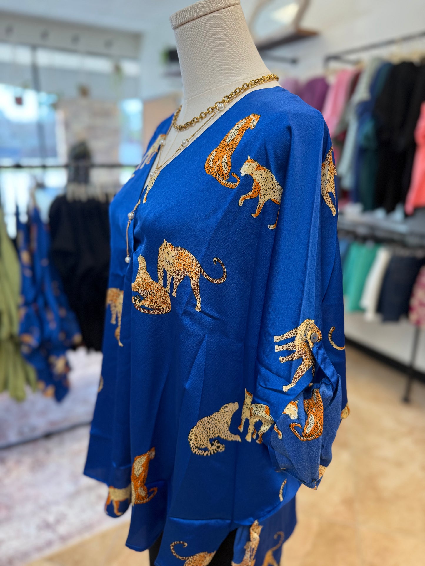 Blue blouse with gold animal patterns on a mannequin in a store setting