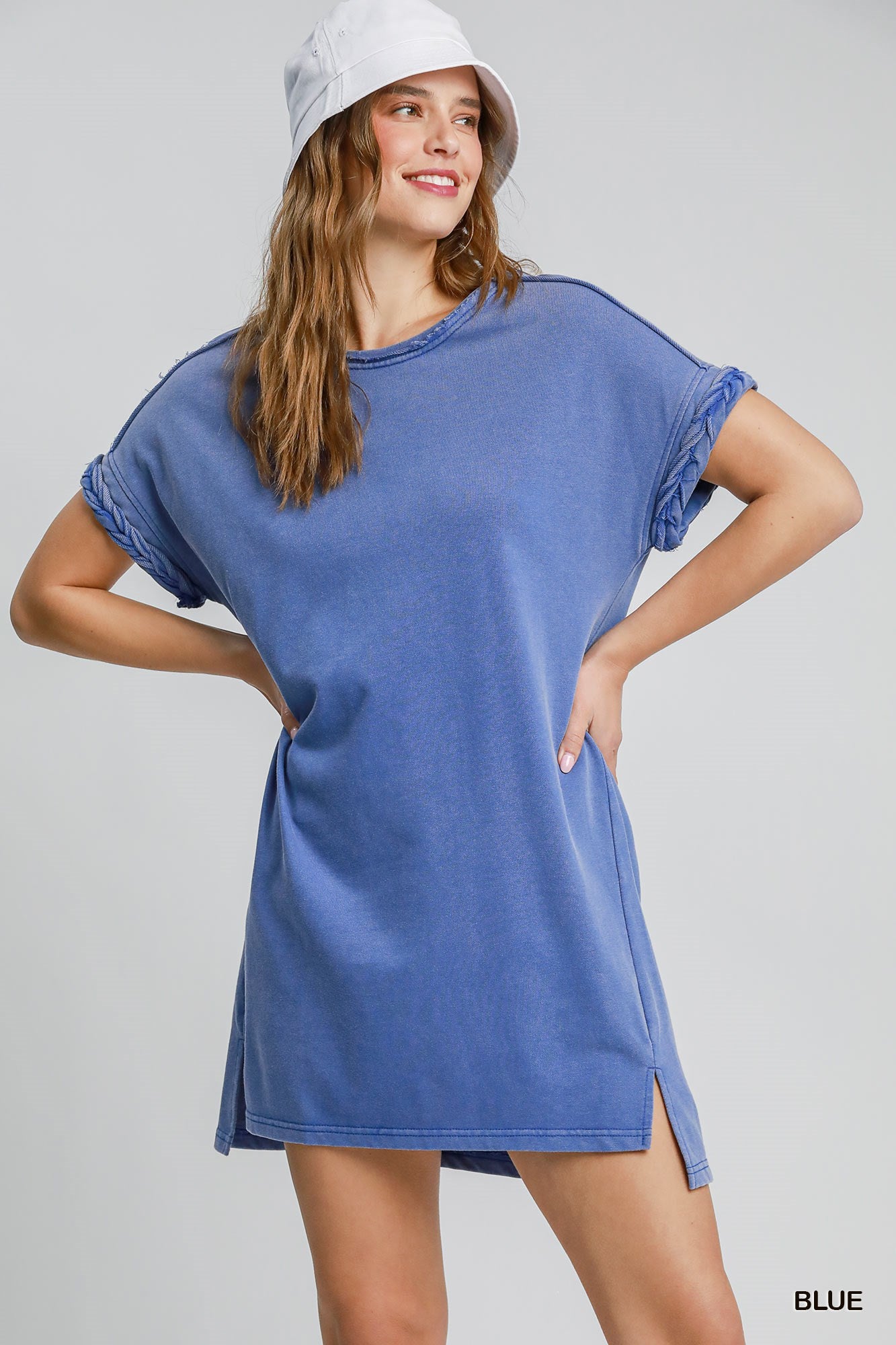 Woman wearing blue dress with braided sleeve detail on a white background