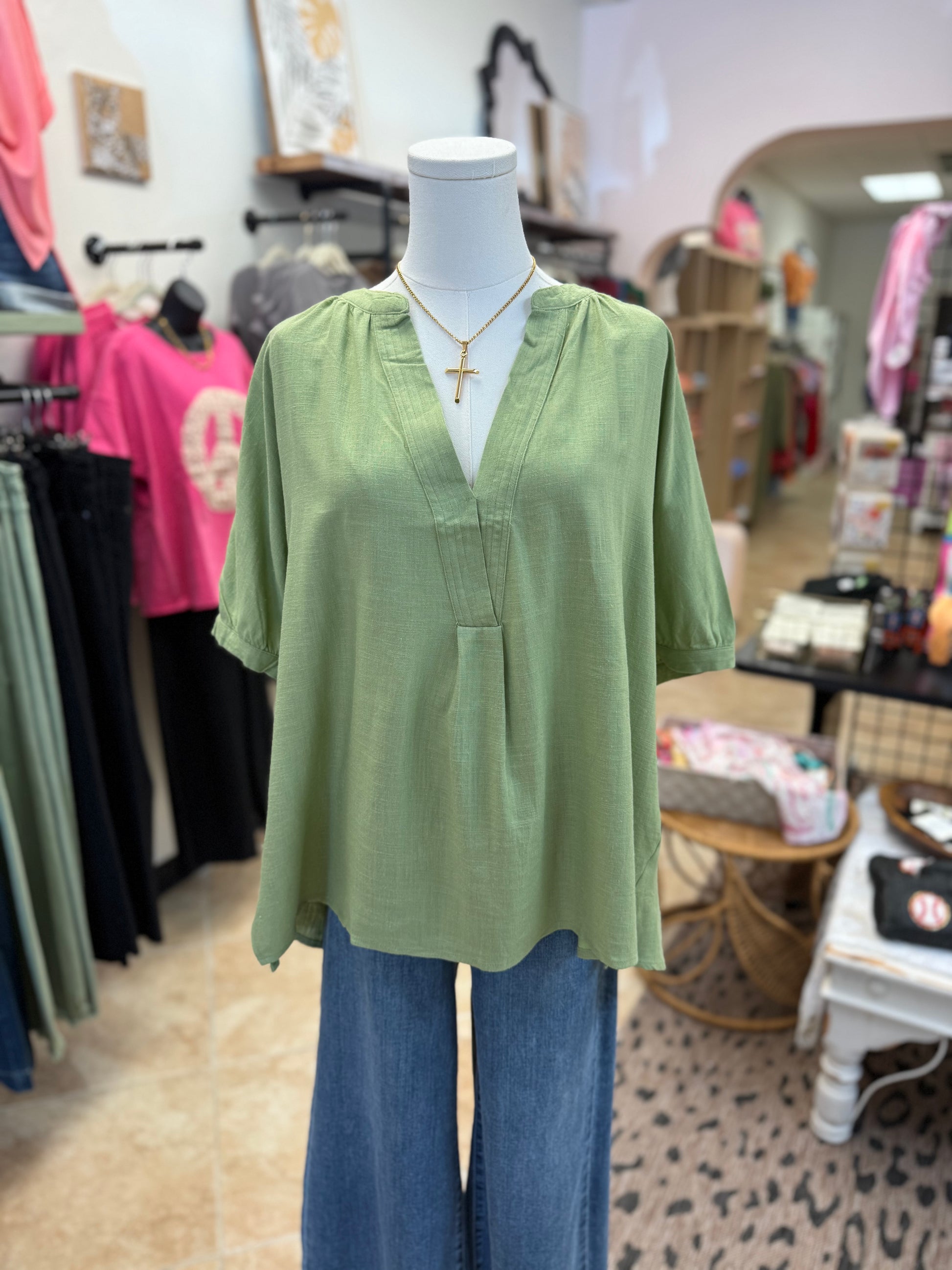 Mannequin wearing a green blouse and blue jeans in a store setting