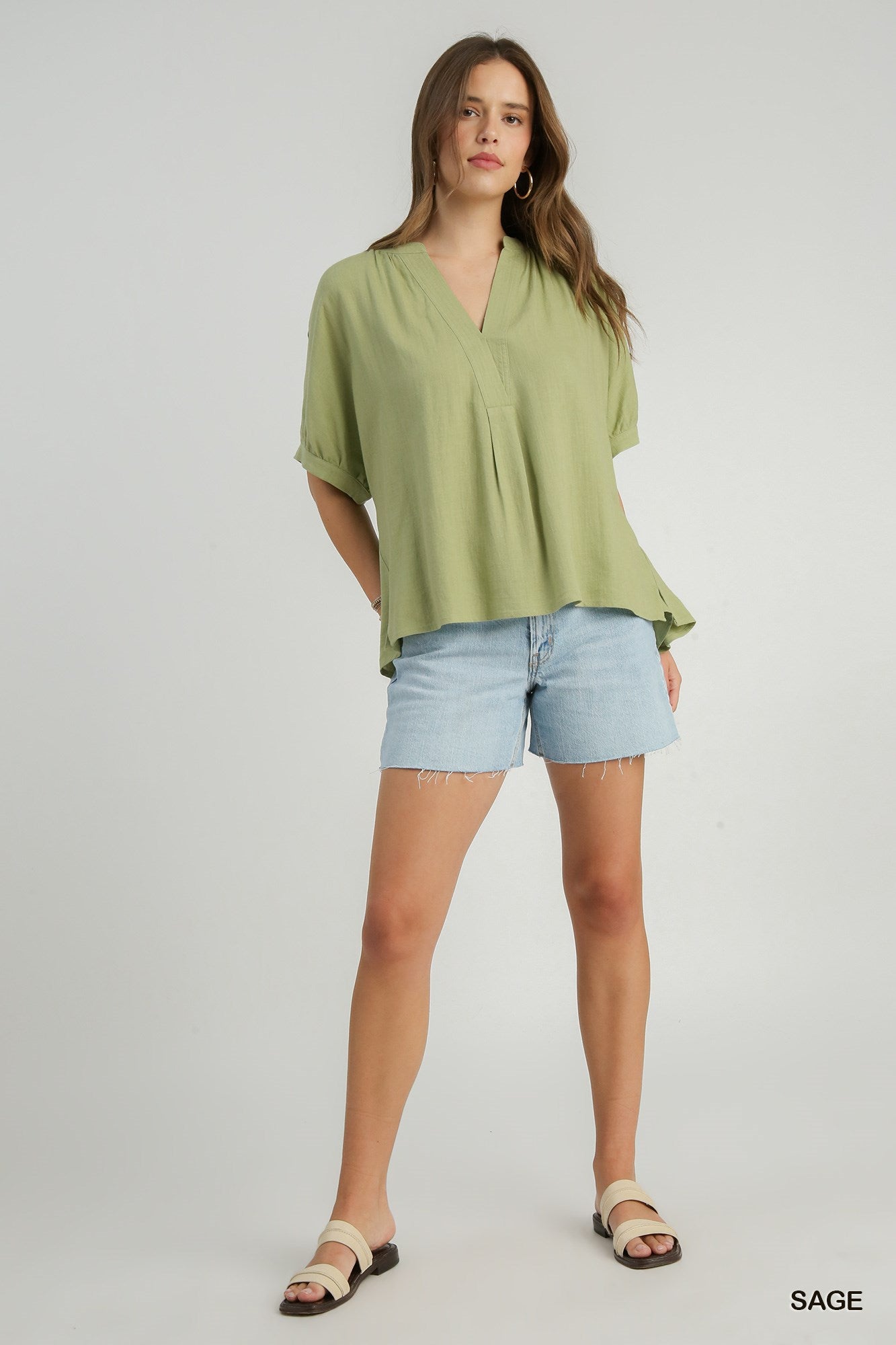 Woman wearing a green blouse and denim shorts on a white background