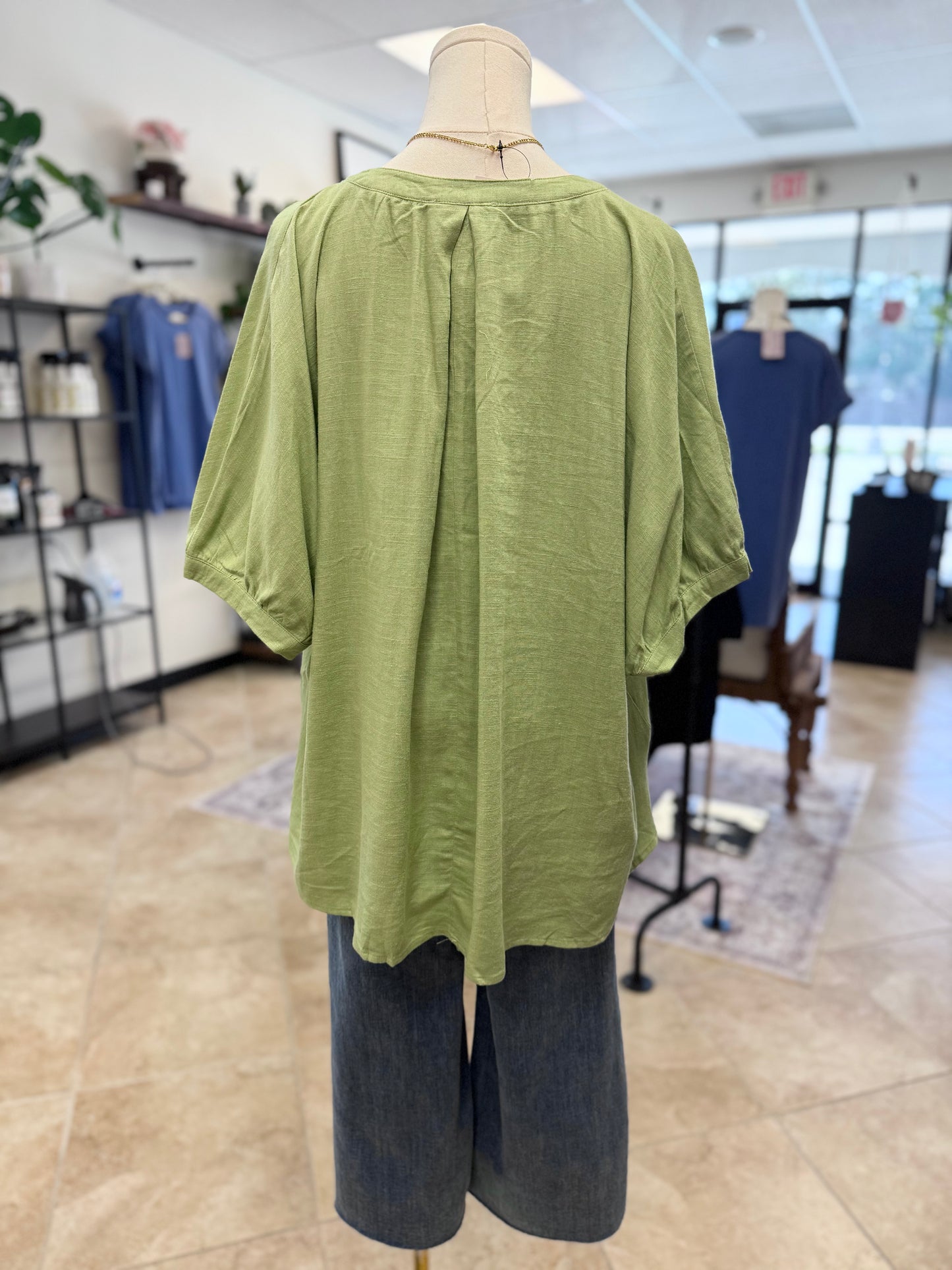 Green top and blue pants on a mannequin in a store setting
