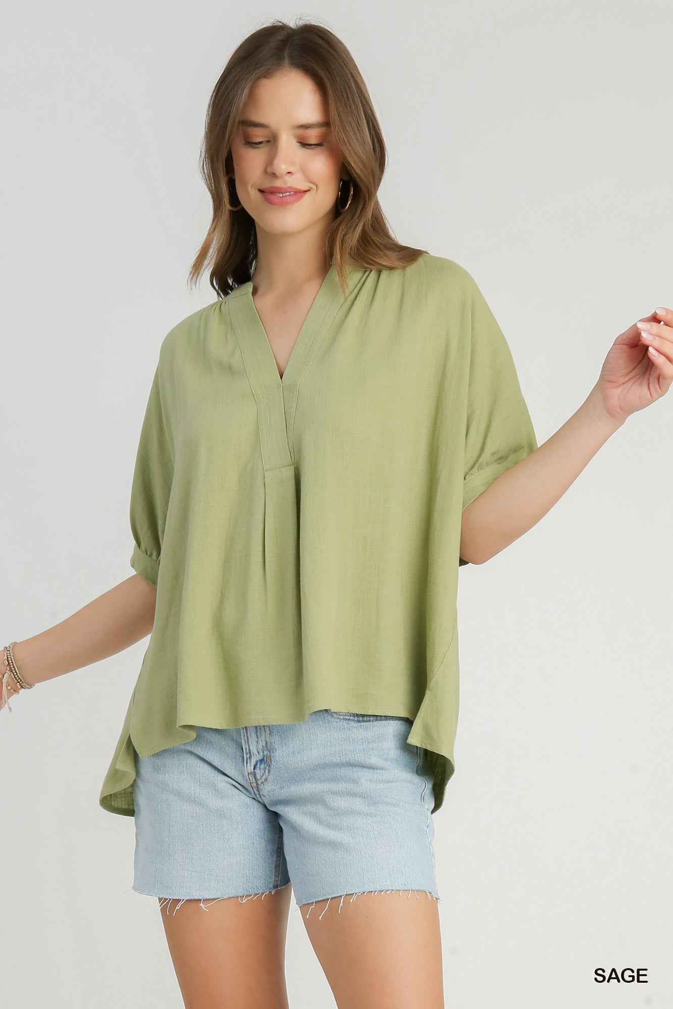 Woman wearing a green blouse and denim shorts on a white background