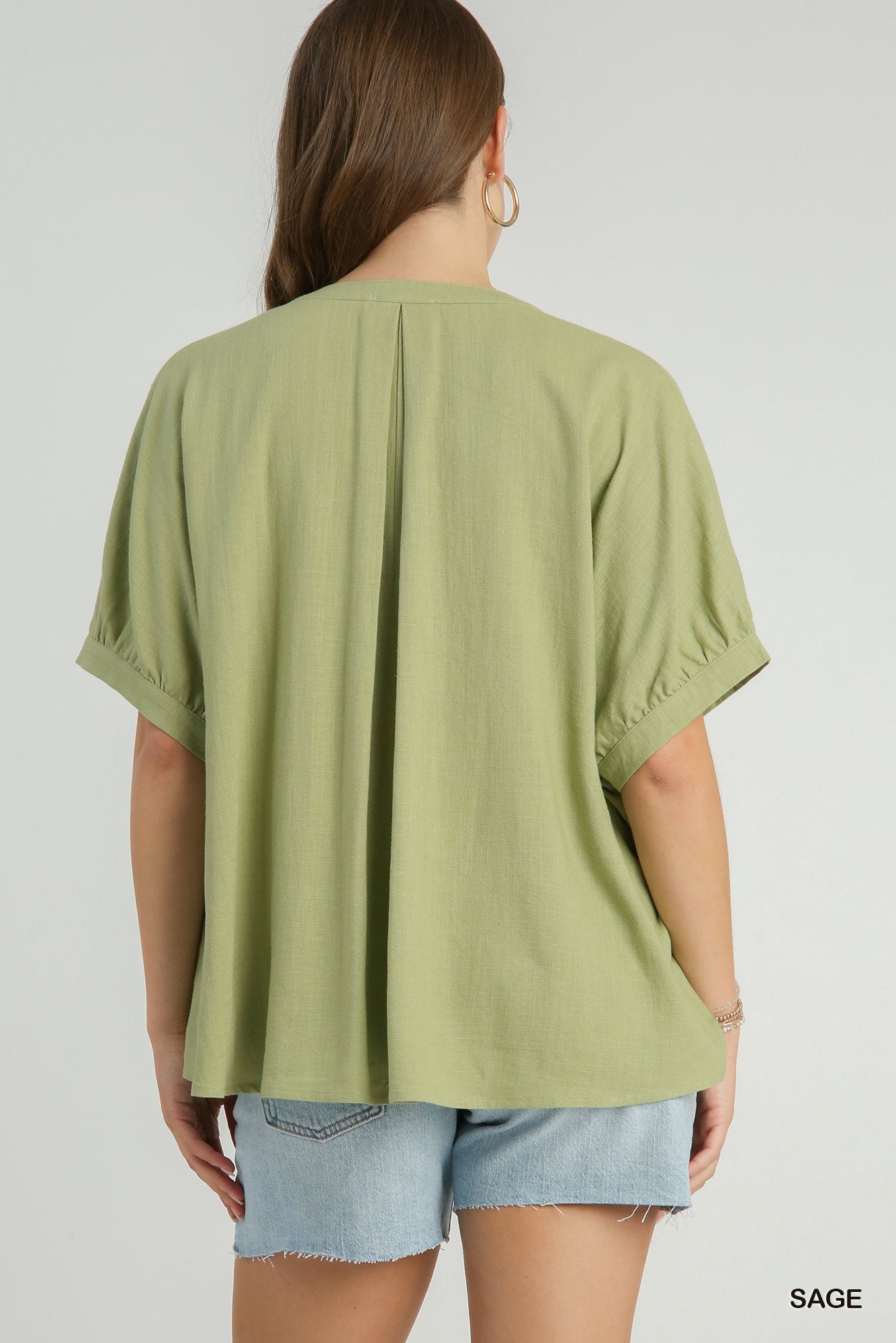 Person wearing a green oversized t-shirt and denim shorts on a white background