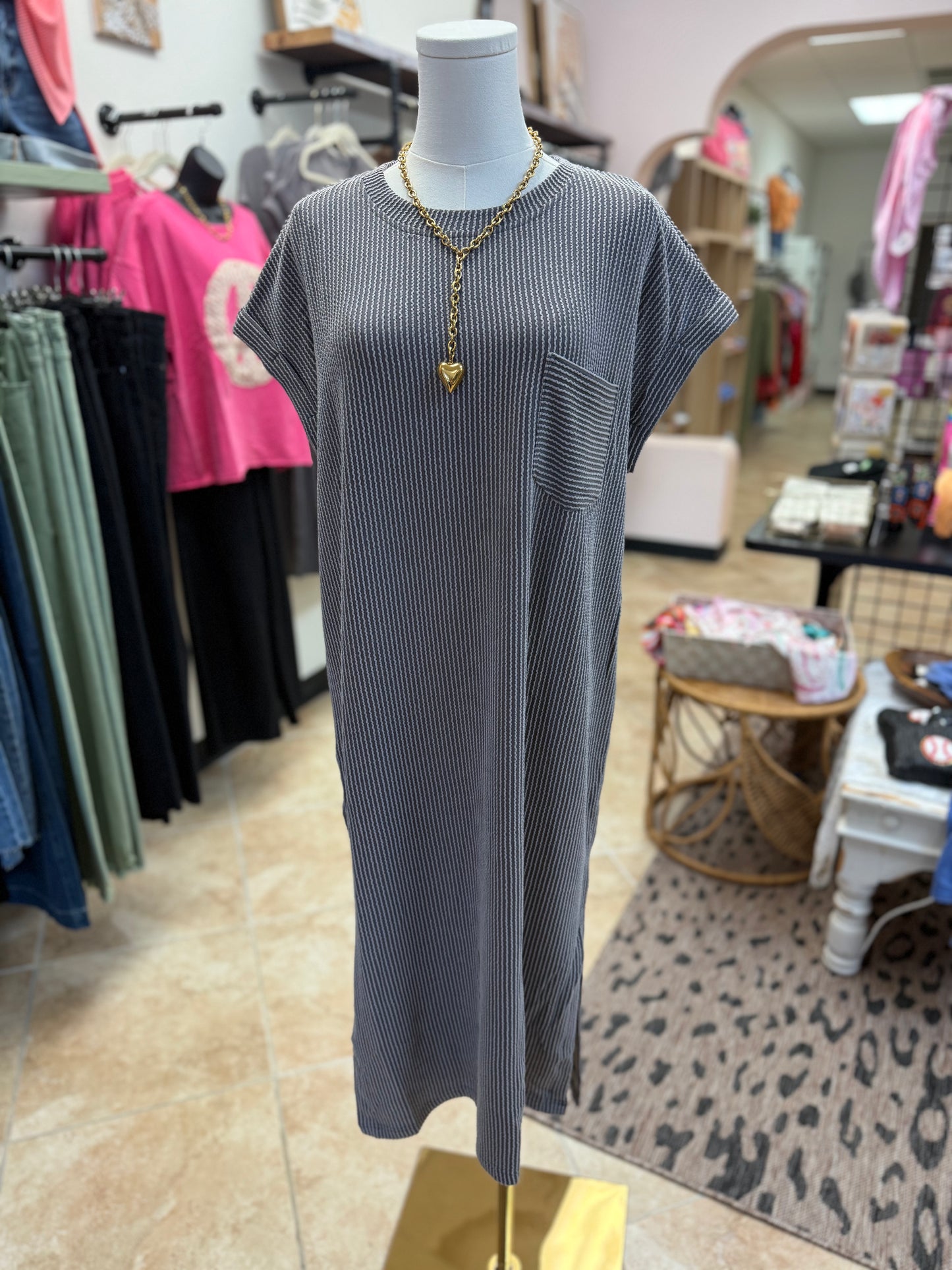 Mannequin wearing a gray dress with a gold necklace in a store setting