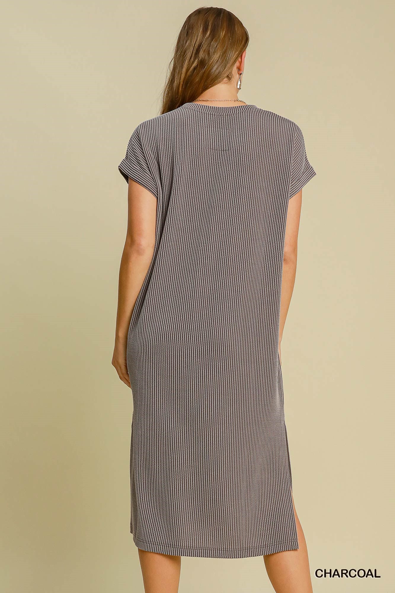 Woman wearing a ribbed knit dress in charcoal color on a beige background