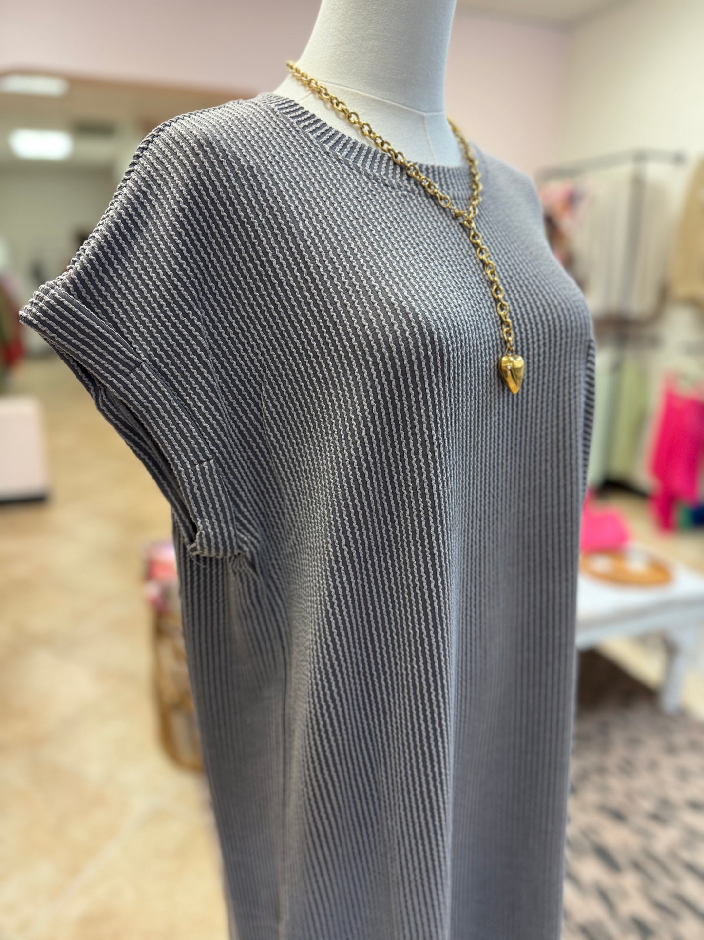 Mannequin wearing a gray dress with a gold necklace in a store setting