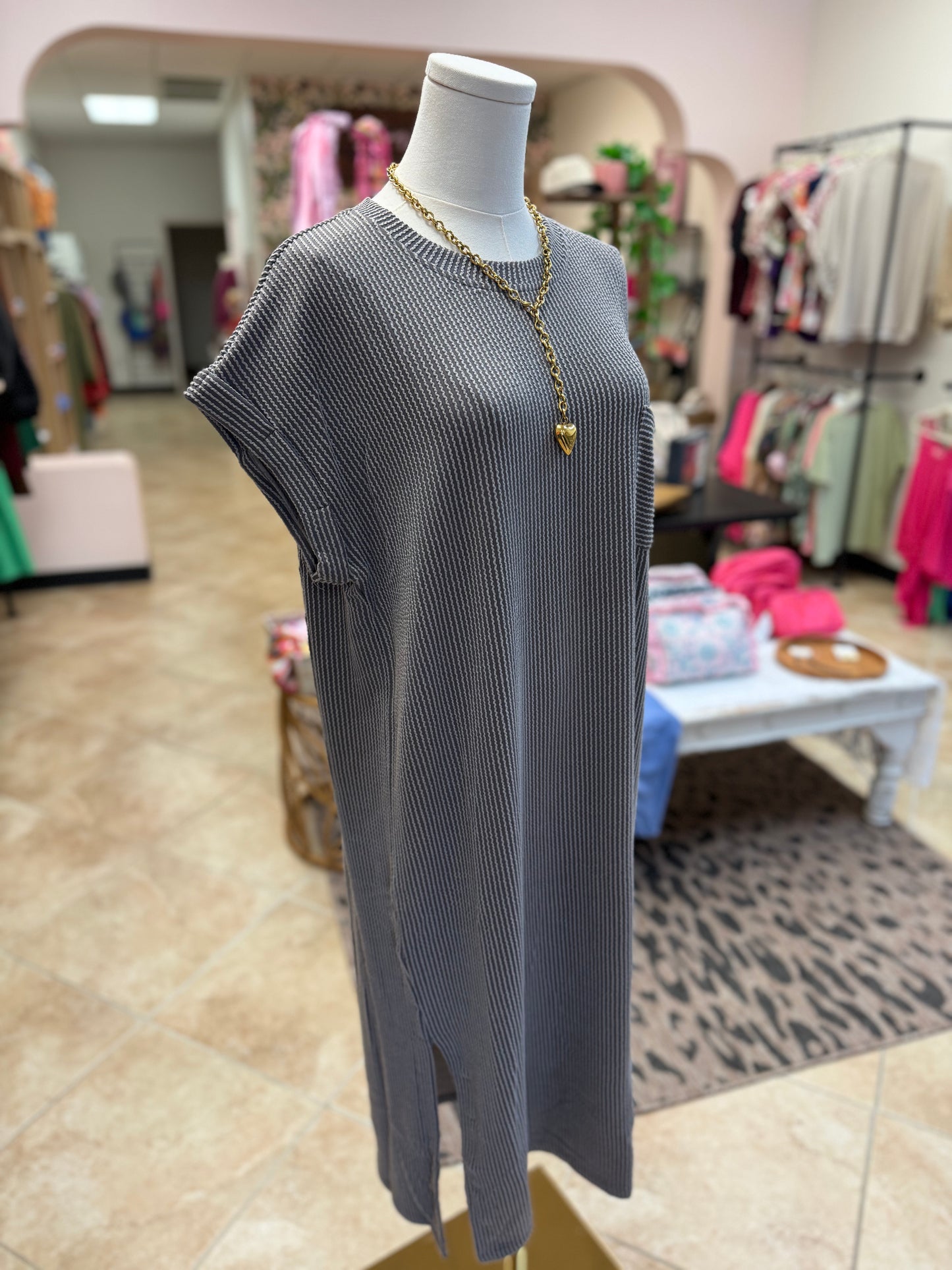 Gray ribbed dress on a mannequin in a store setting with clothing racks and displays in the background.
