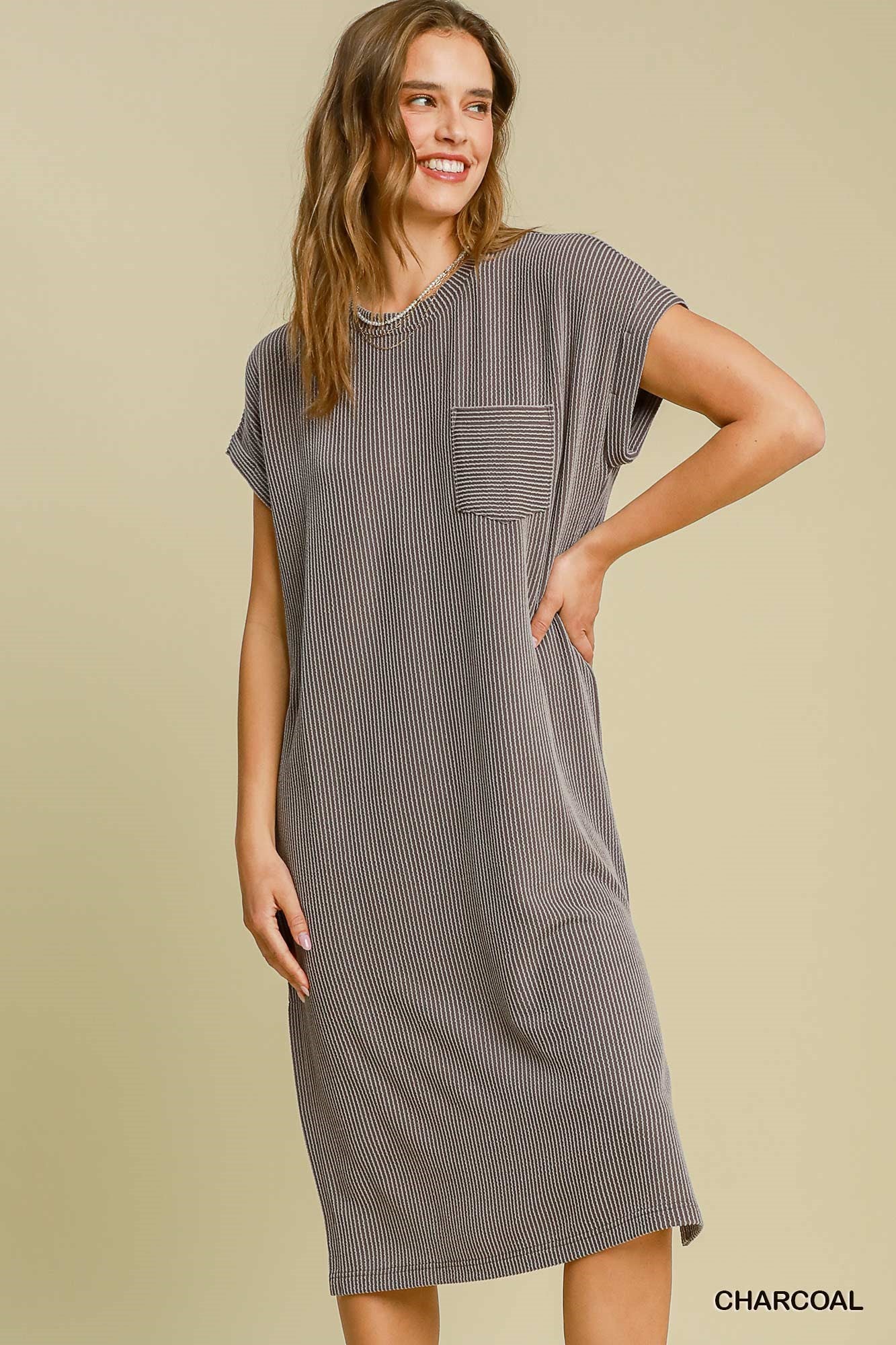Woman wearing a gray dress with a pocket on a beige background