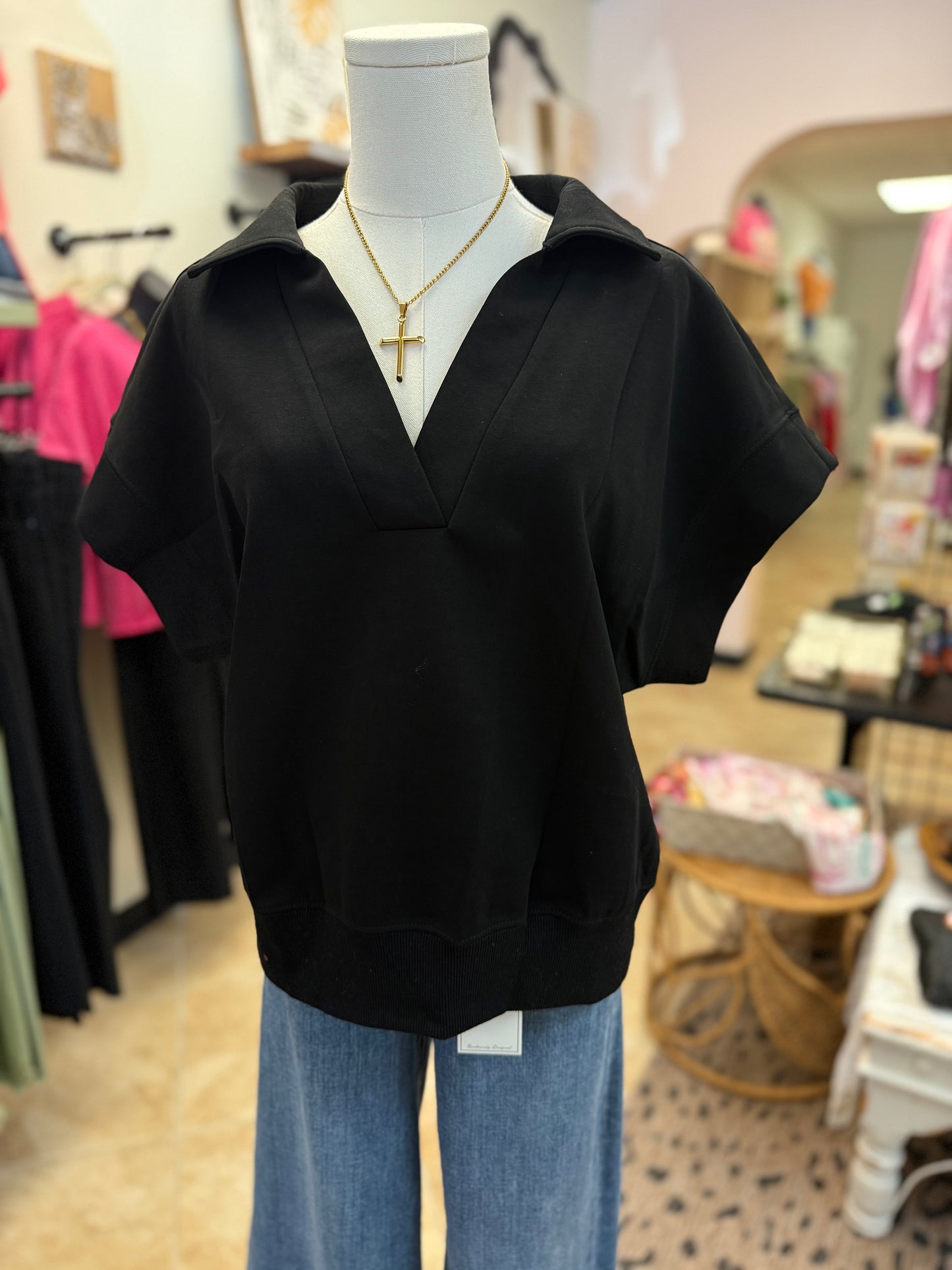 Black top on a mannequin with blue jeans in a store setting