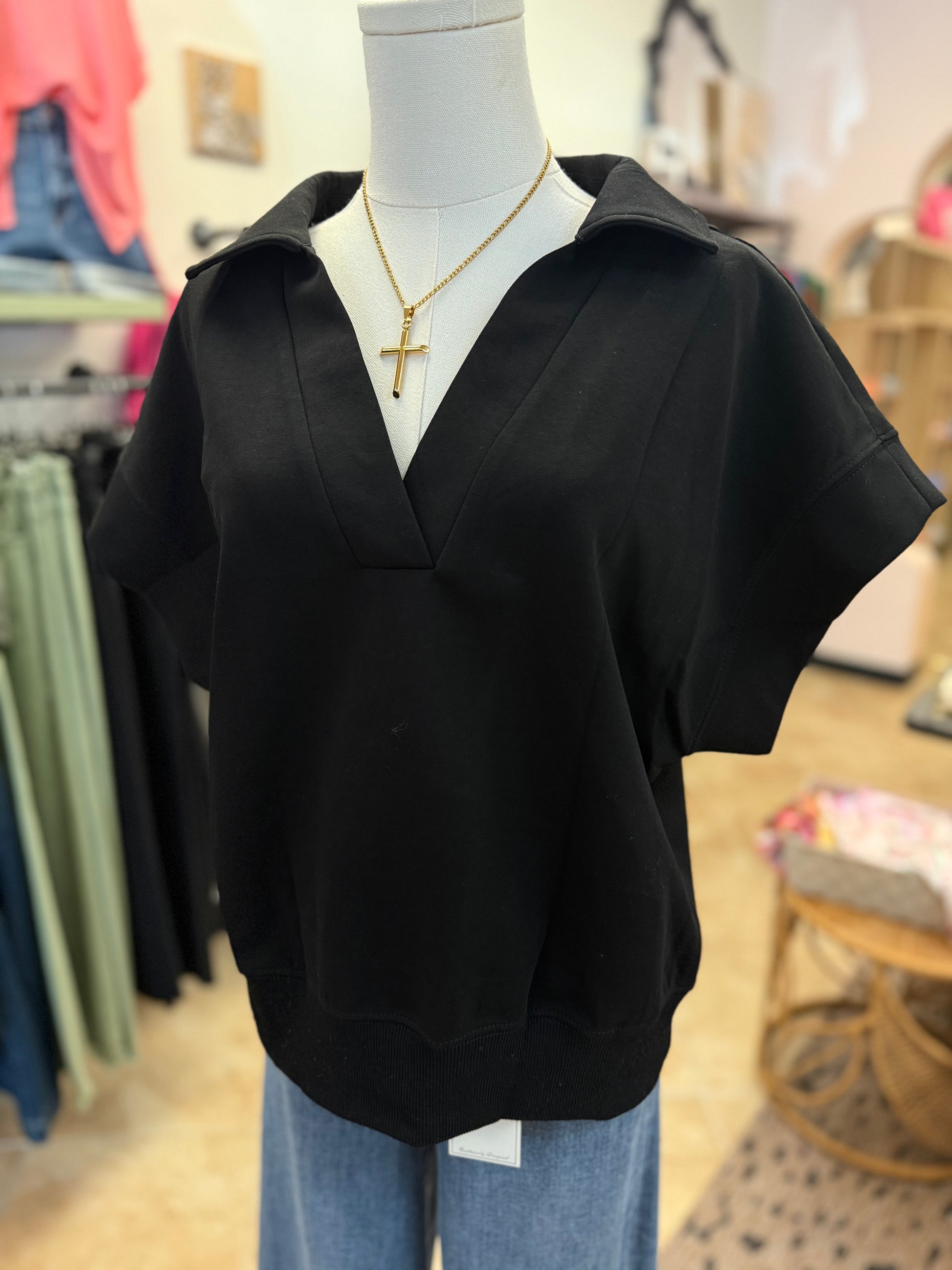 Black top on a mannequin with a blurred store background