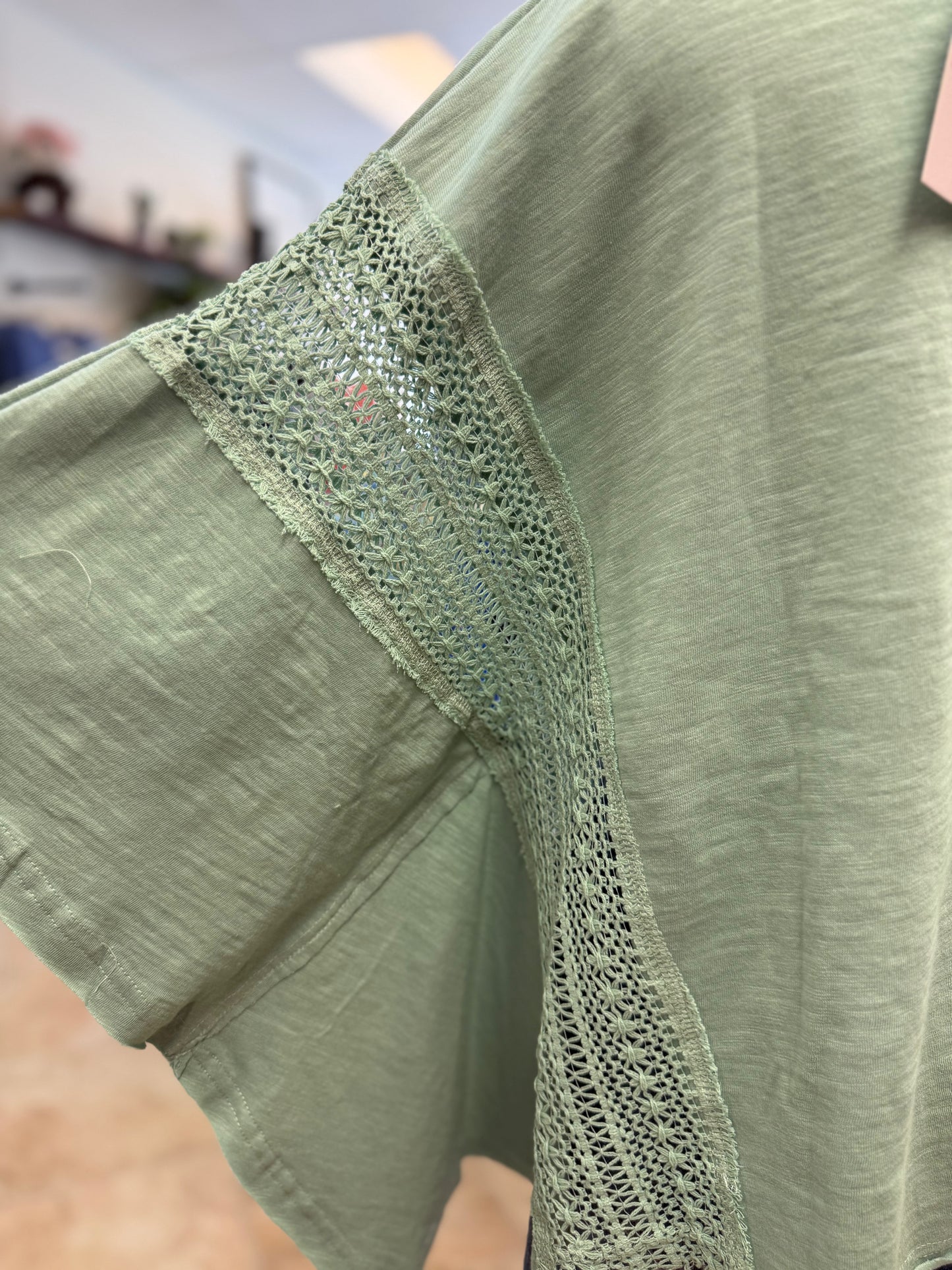 Teal shirt with lace trim on a blurred background