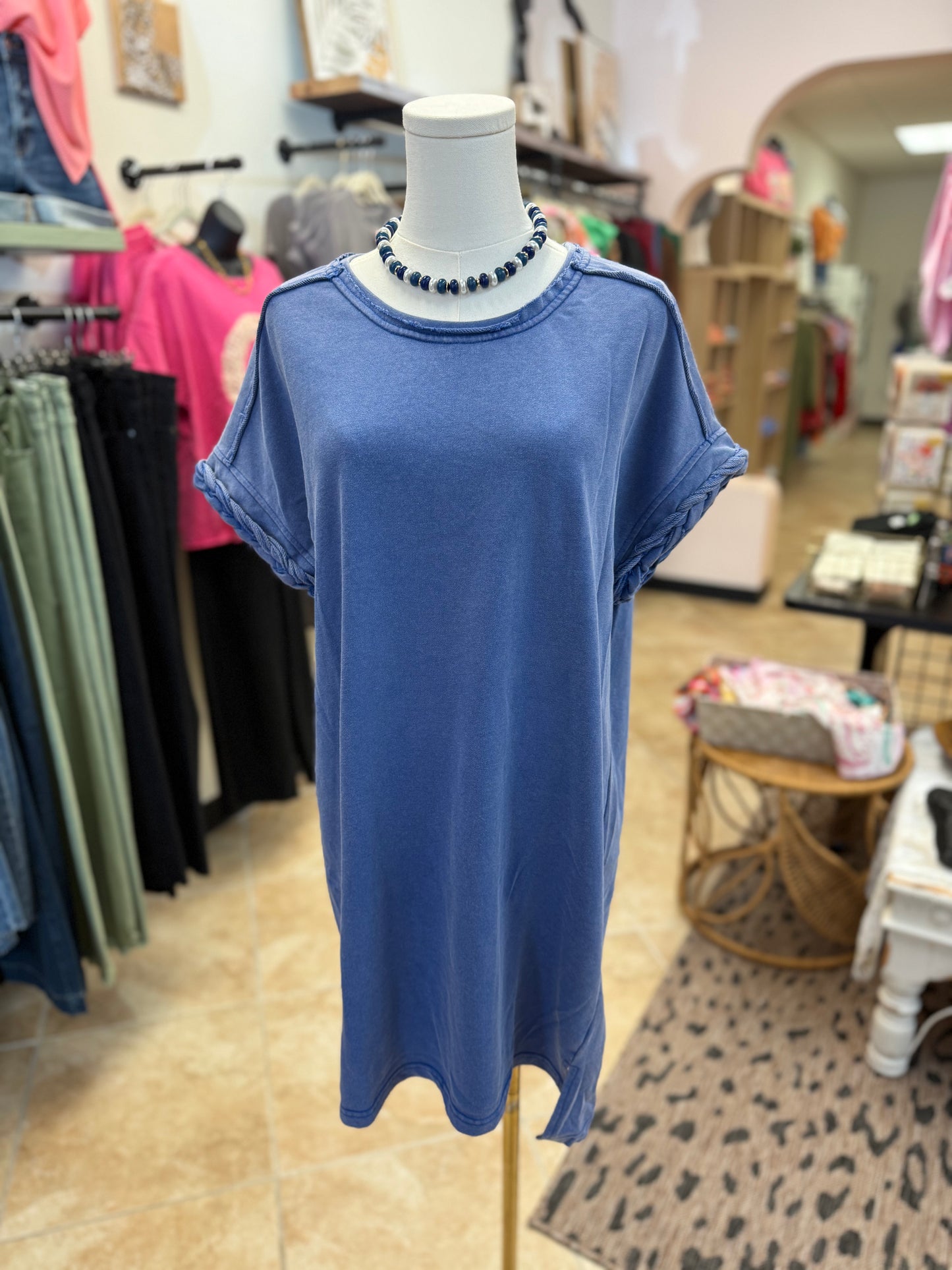 Blue dress with braided sleeve detail on a mannequin in a store setting