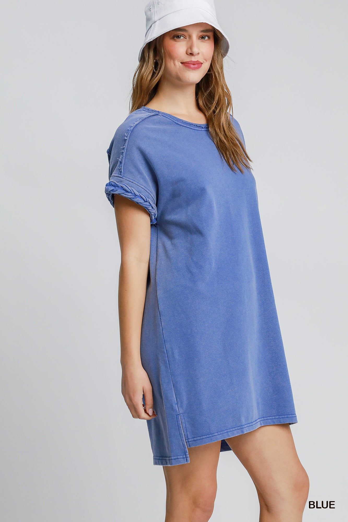 Woman wearing blue dress with braided sleeve detail on a white background