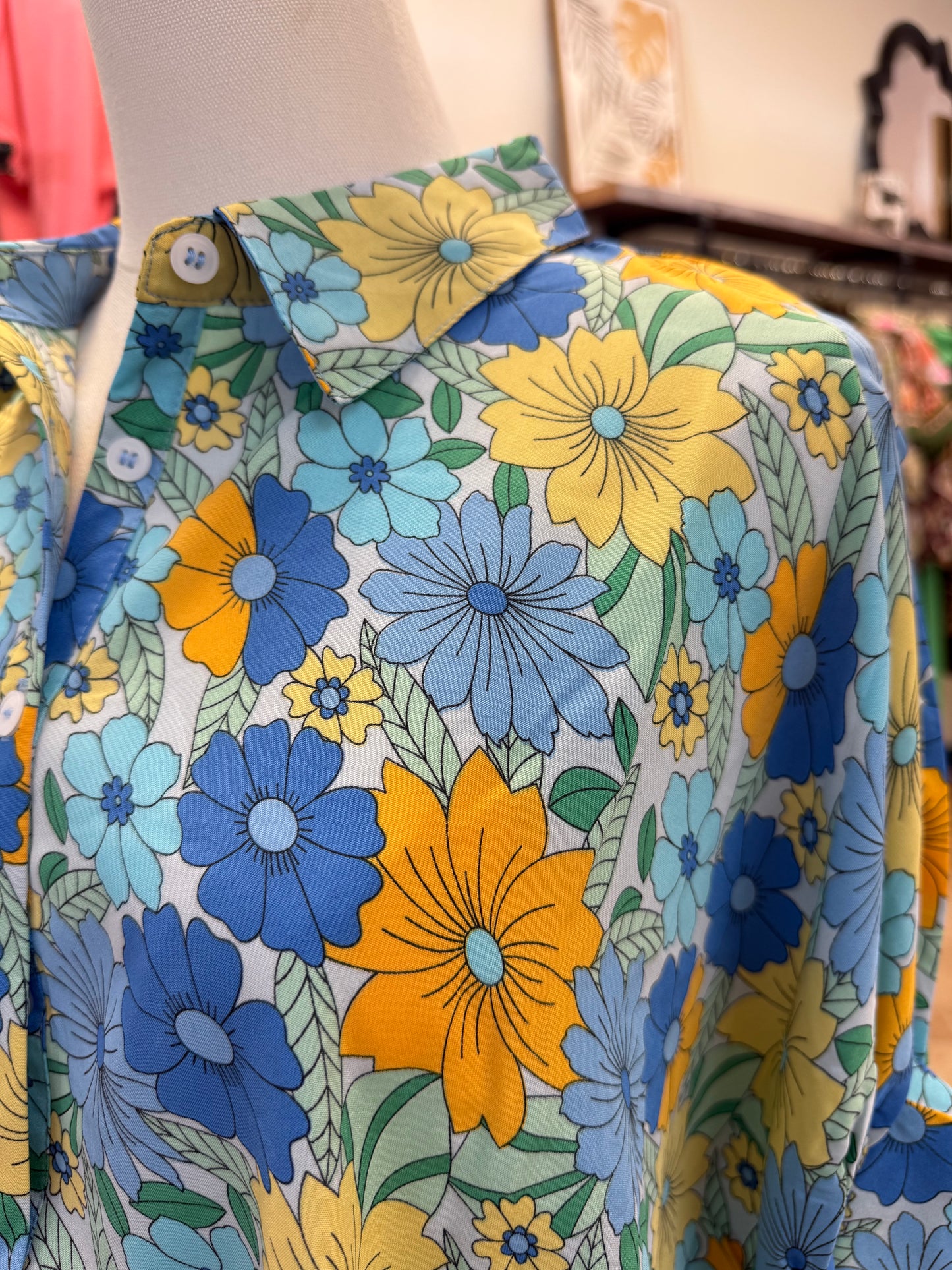 Close up of colorful blue floral button up blouse with collar and jeans