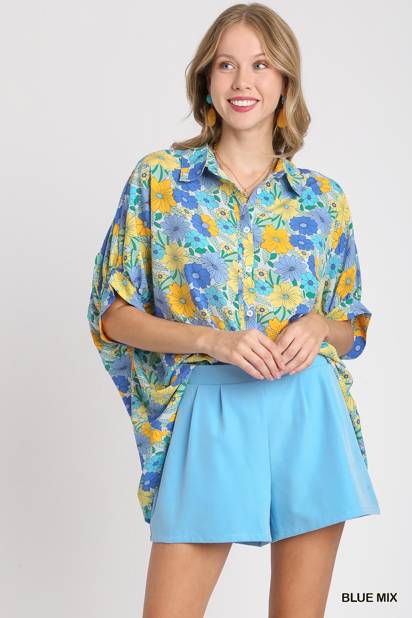 Woman wearing a floral blouse and light blue skirt on a white background