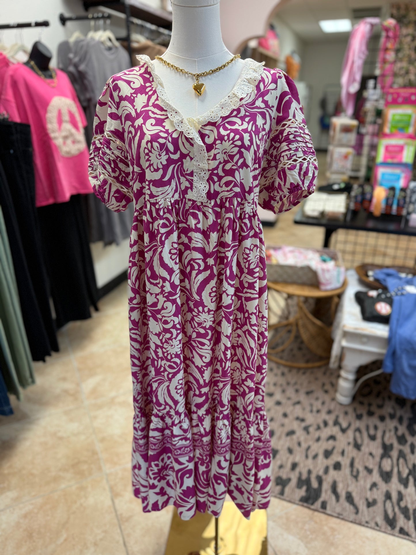 Magenta floral dress with lace detail on a mannequin with gold necklace