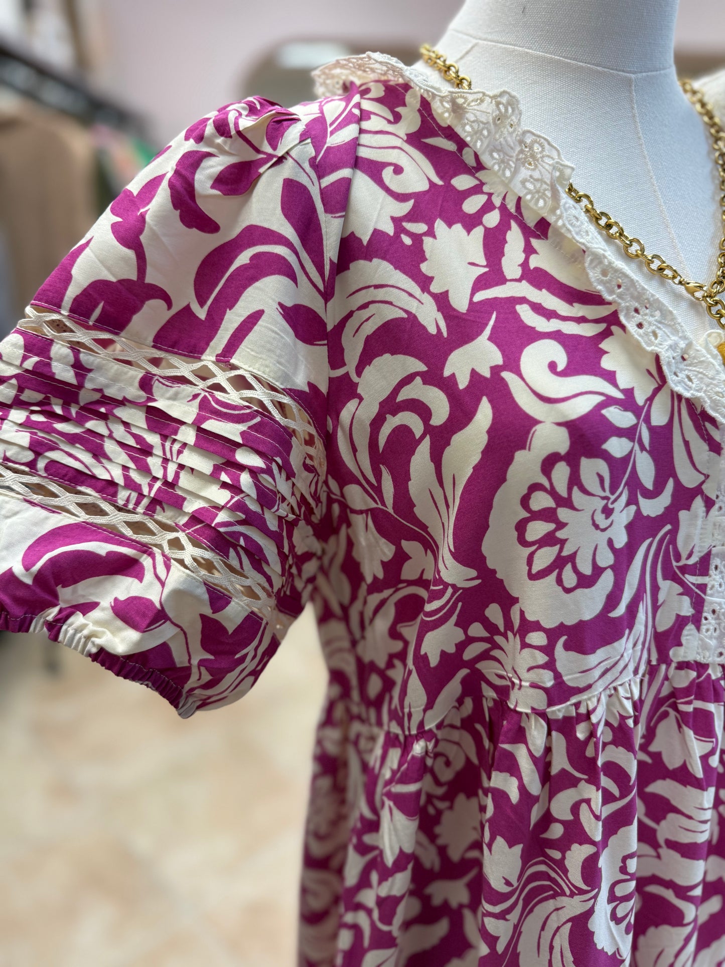 Mannequin wearing a purple and white patterned dress with lace collar.