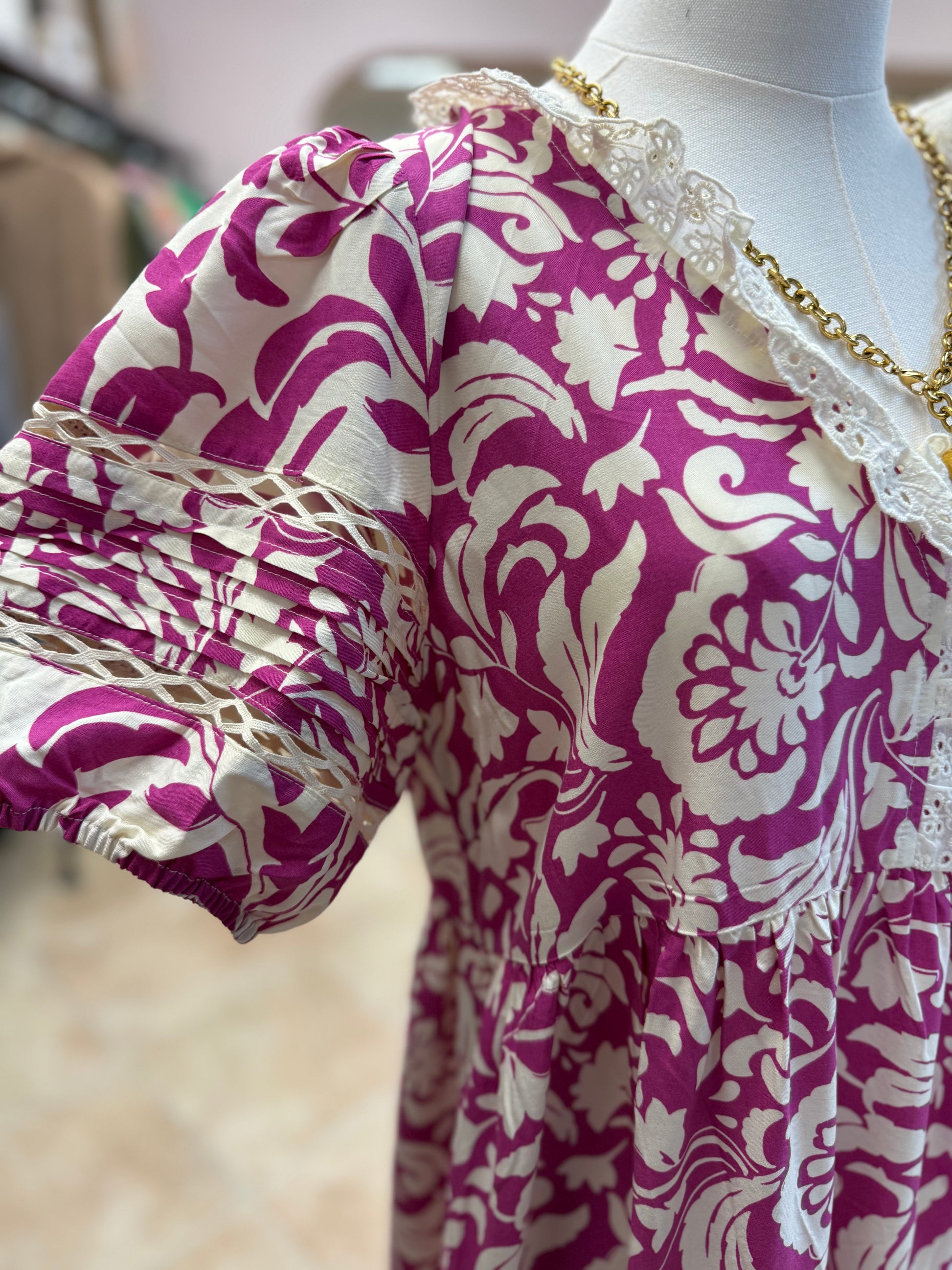 Mannequin wearing a purple and white patterned dress with lace collar.