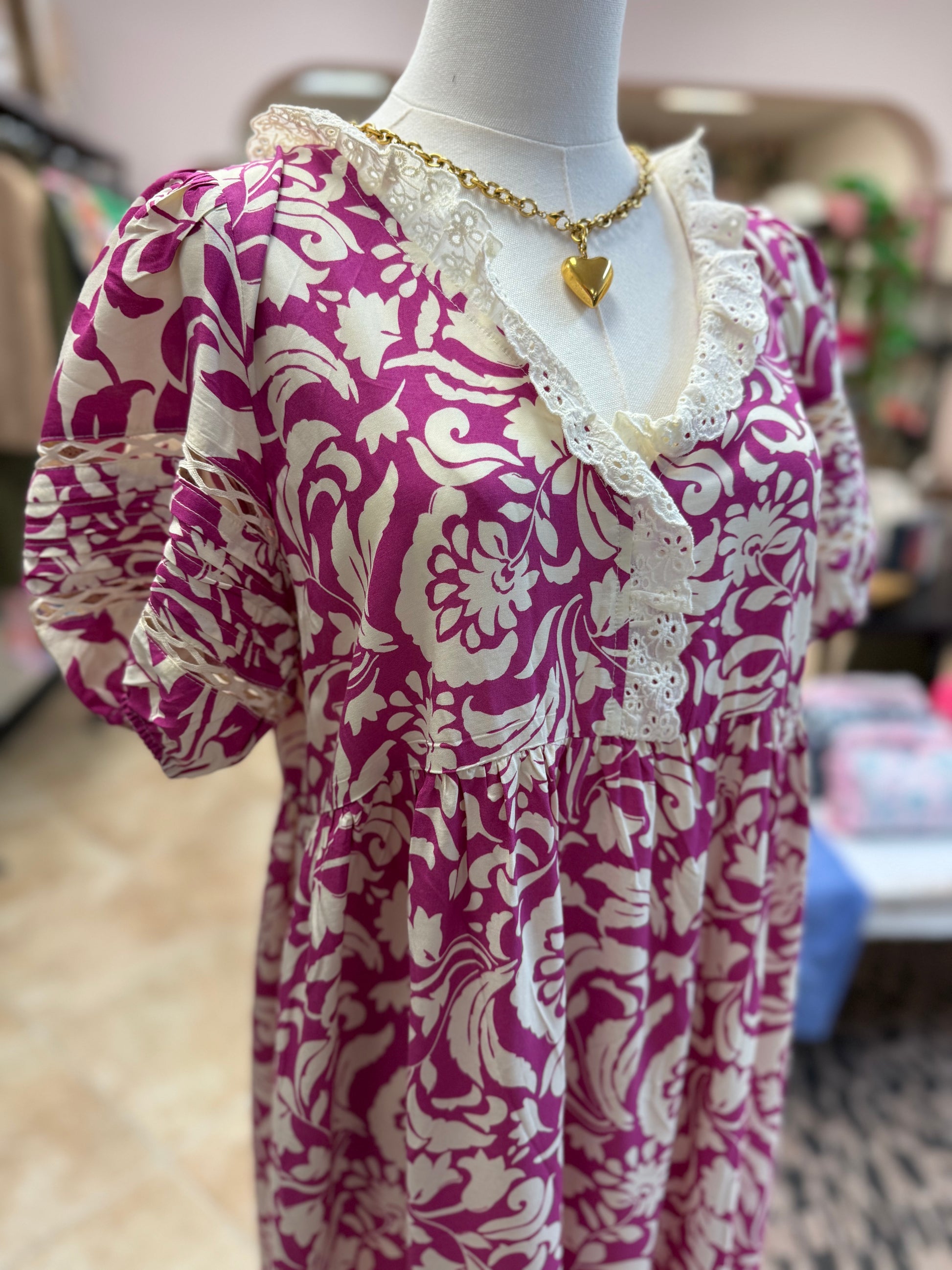 Mannequin wearing a pink and white patterned dress with a blurred background