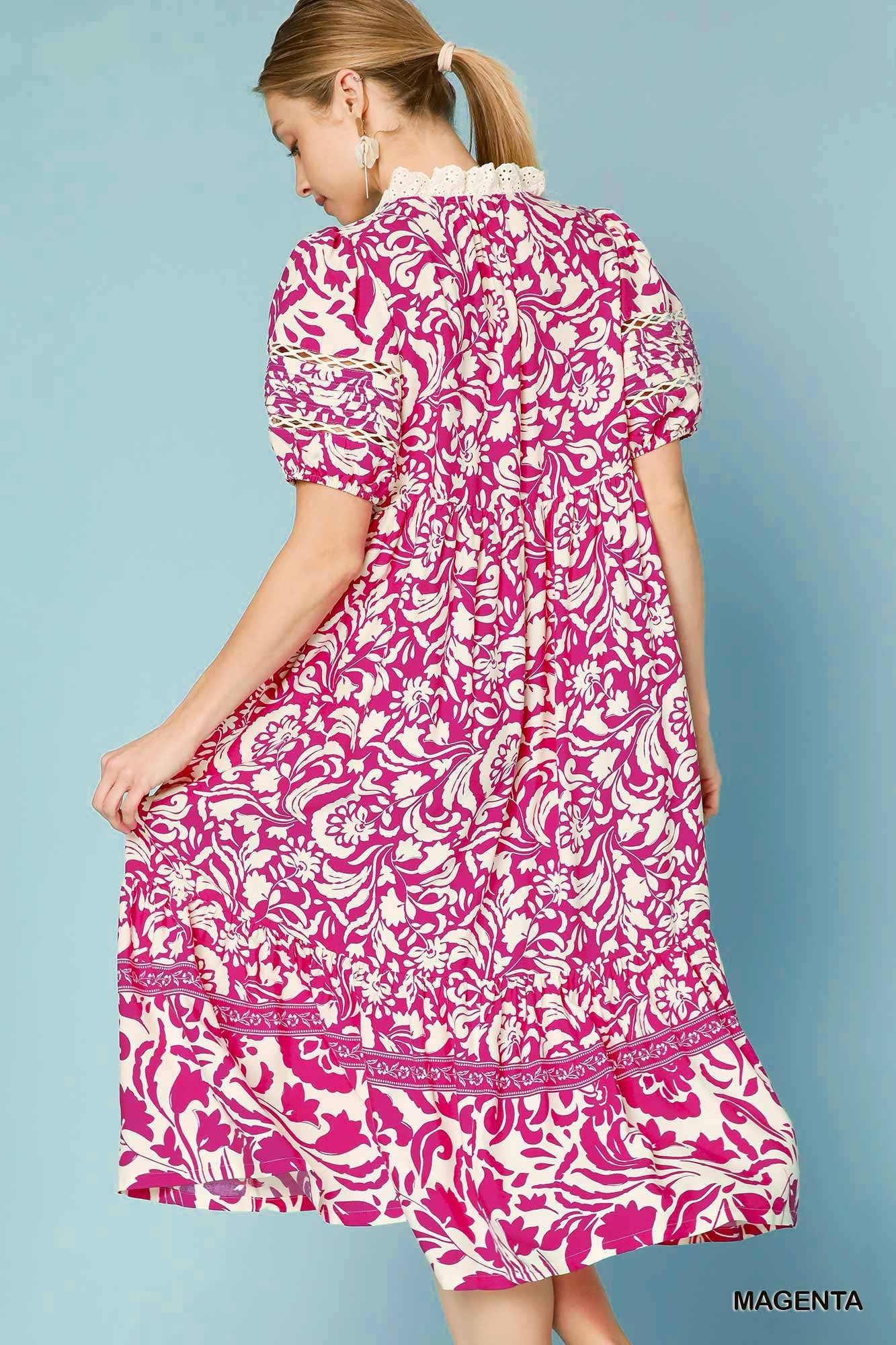 Woman wearing a pink and white patterned dress against a blue background