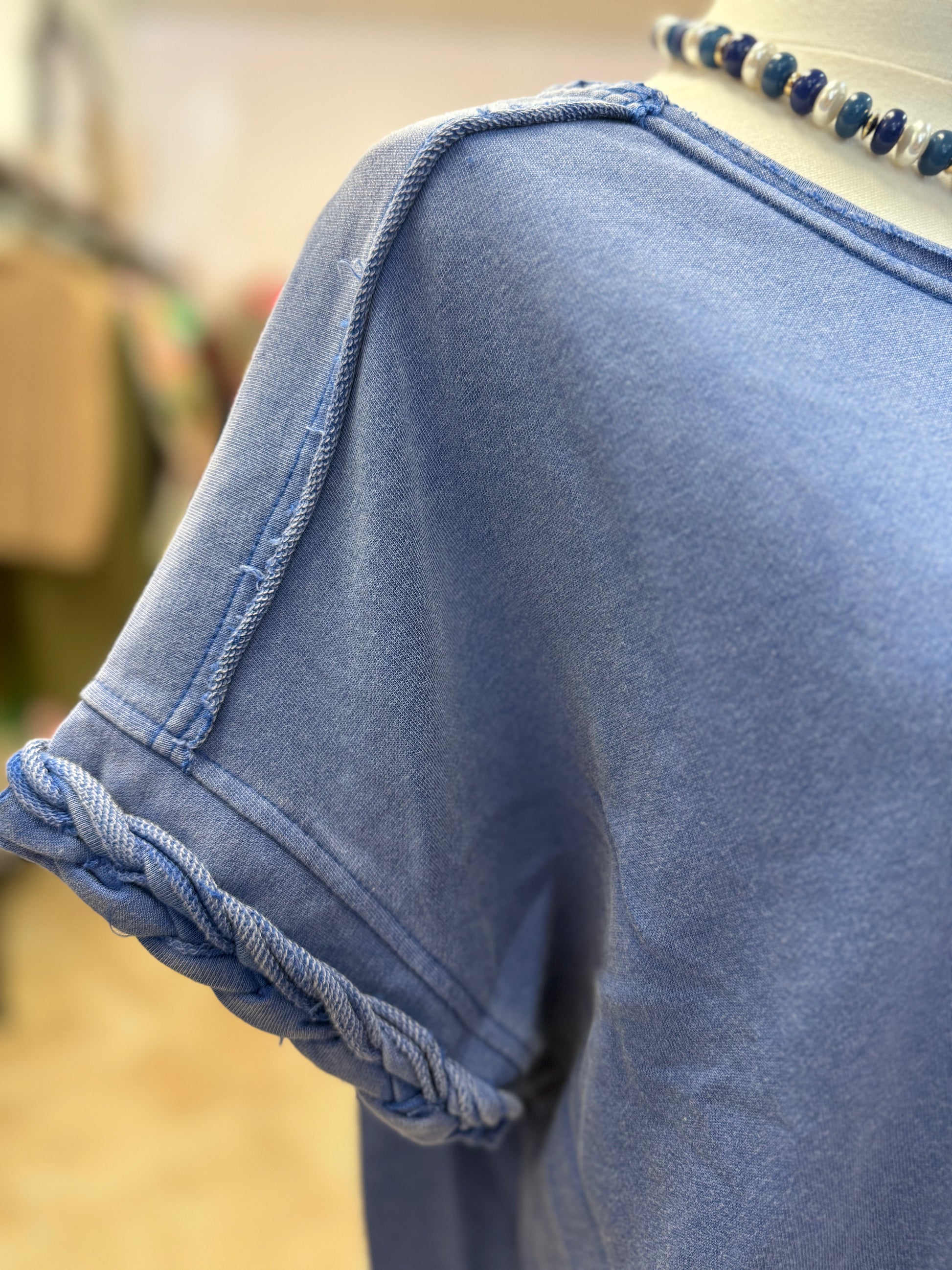 Up close of blue dress with braided sleeve detail on a mannequin in a store setting